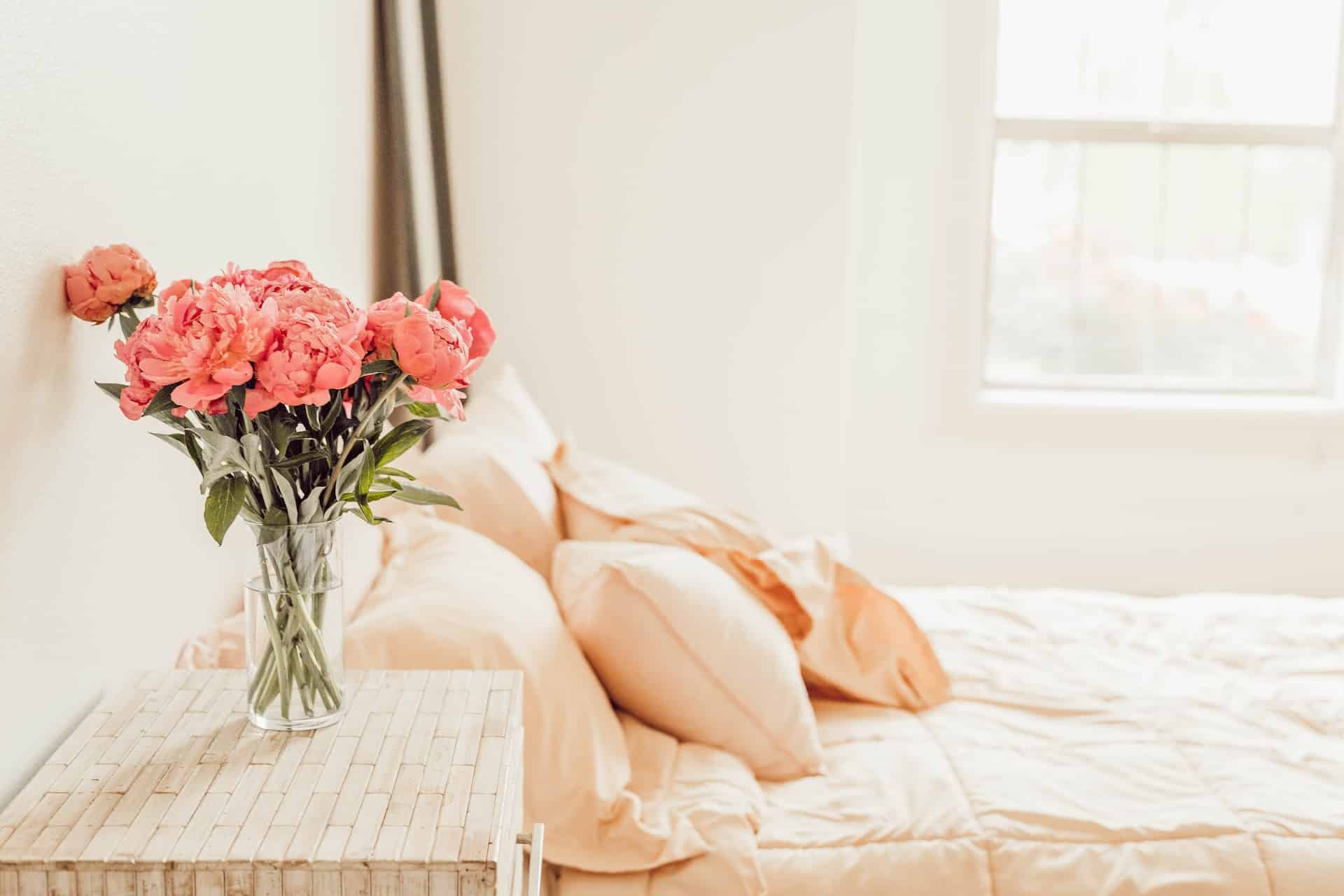 roses in a vase on a bed stand