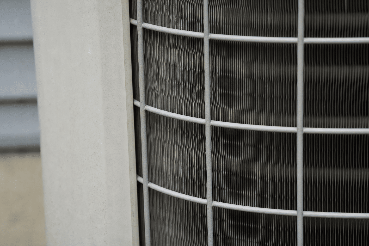 Close-up of air conditioner condenser coil fins and fan grille