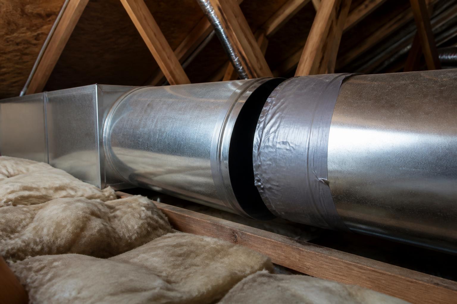 Residential duct system's sheet-metal ductwork running through an unfinished attic space beside insulation