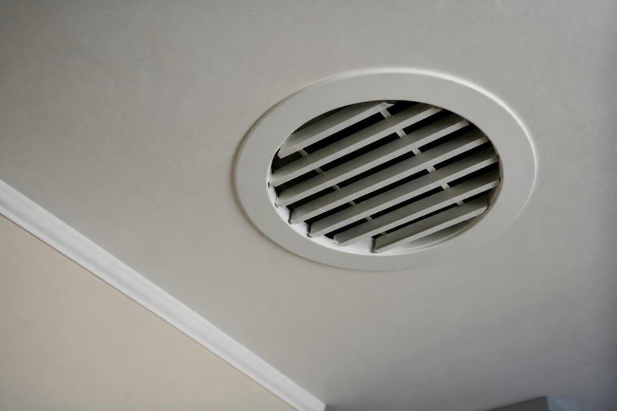 Clean round HVAC return air vent grille on a hallway ceiling